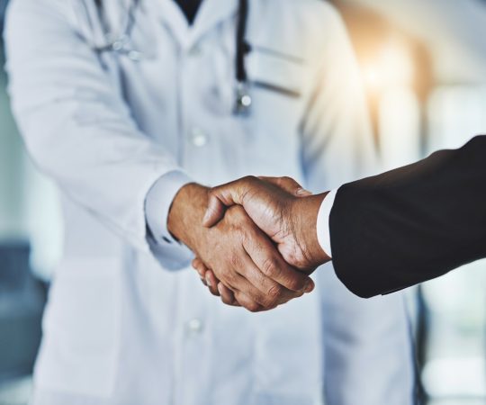 Cropped shot of a doctor shaking hands with a businessman in a hospital